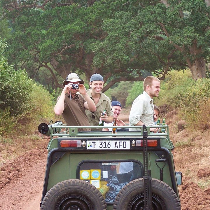 Adam Young and friends in a safari truck on a red-dirt road in Tanzania