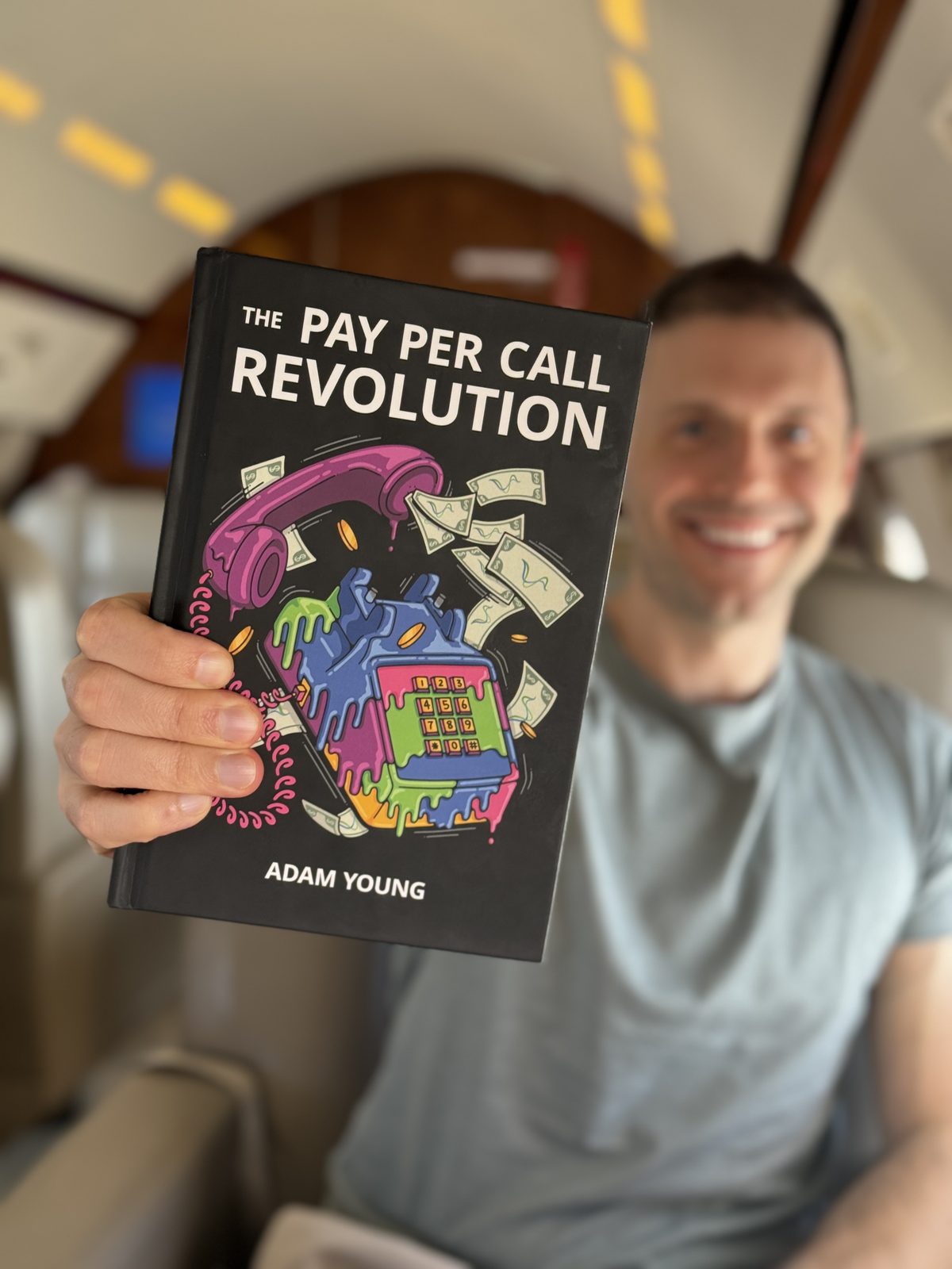 Adam Young aboard a private jet holding a hardcover of The Pay Per Call Revolution