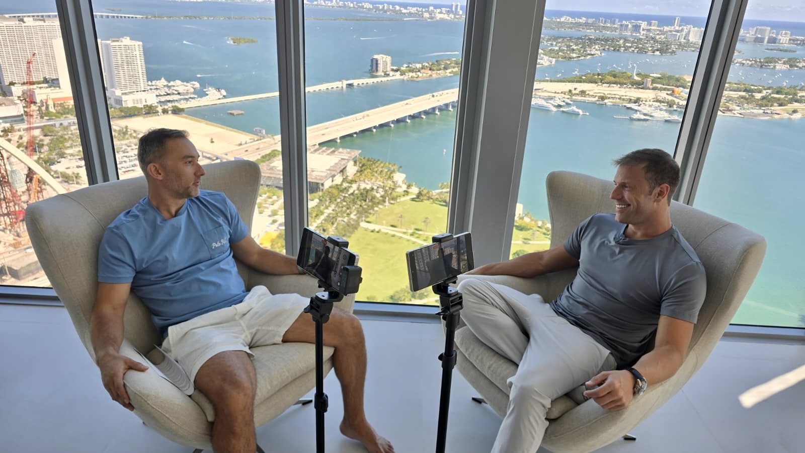 Adam Young recording a conversation in two chairs high above Biscayne Bay