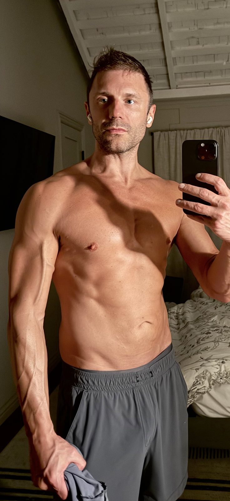 Adam Young flexing in a gym mirror after the transformation