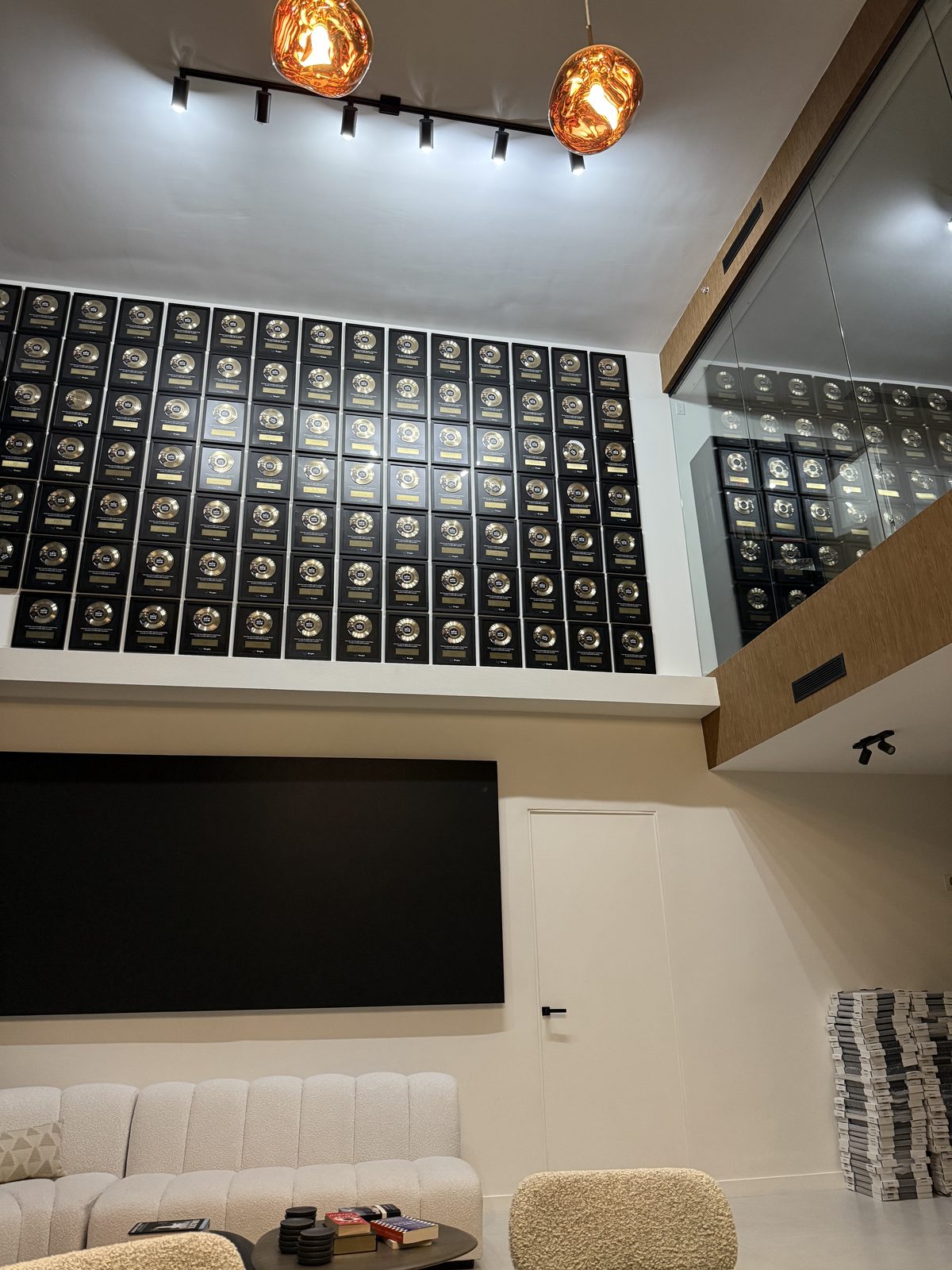 A wall of framed GOAT Club record plaques in a designer lounge