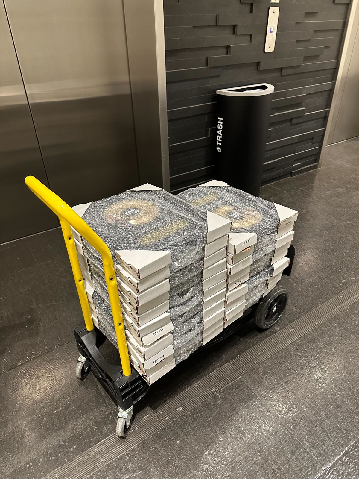 A cart stacked with bubble-wrapped GOAT Club plaques ready to ship to winners