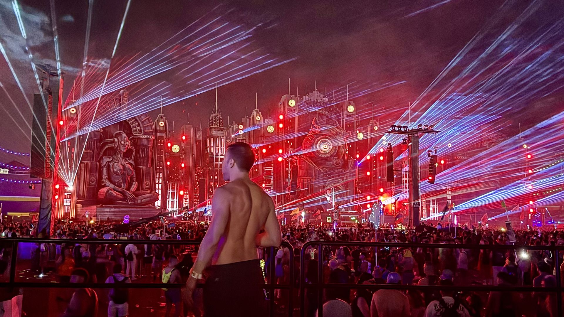 Adam Young facing a wall of lasers above the crowd at a festival main stage