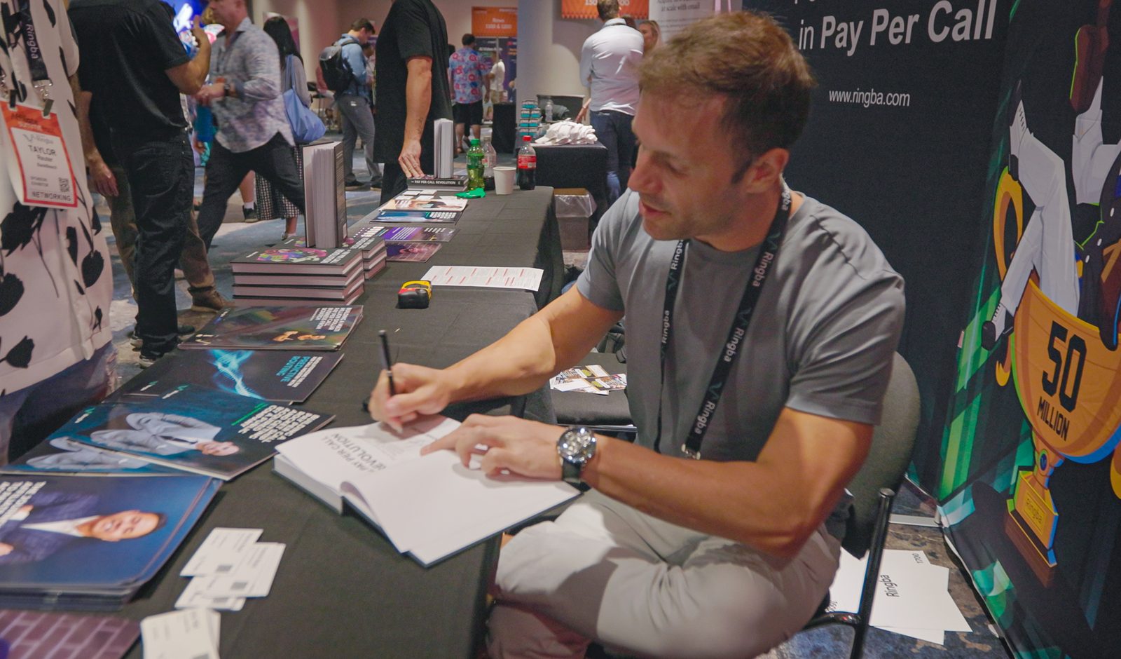 Adam Young signing copies of his book at the Ringba trade show booth