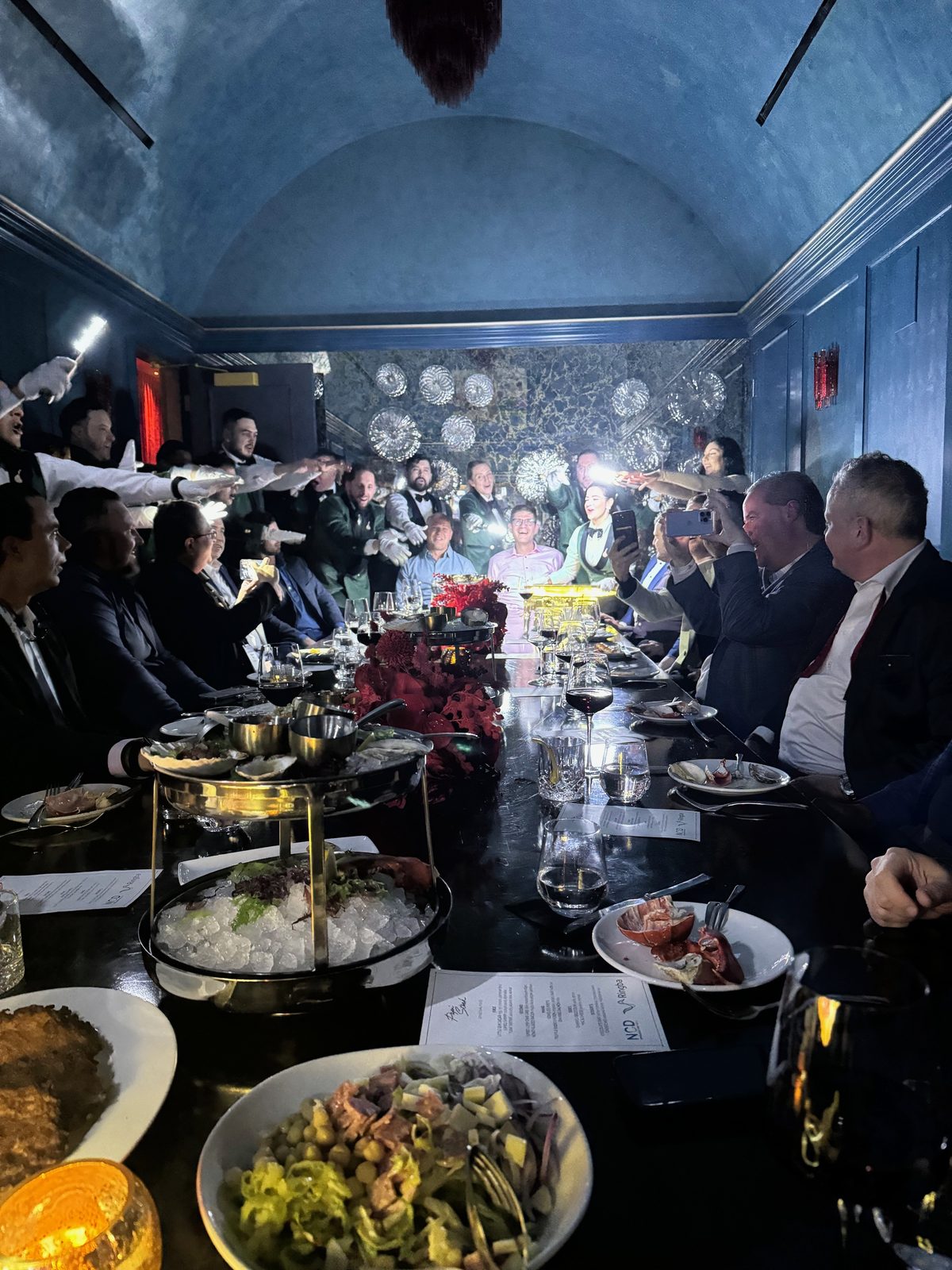 A Ringba private dinner with sparkler-lit dishes carried through a vaulted blue dining room